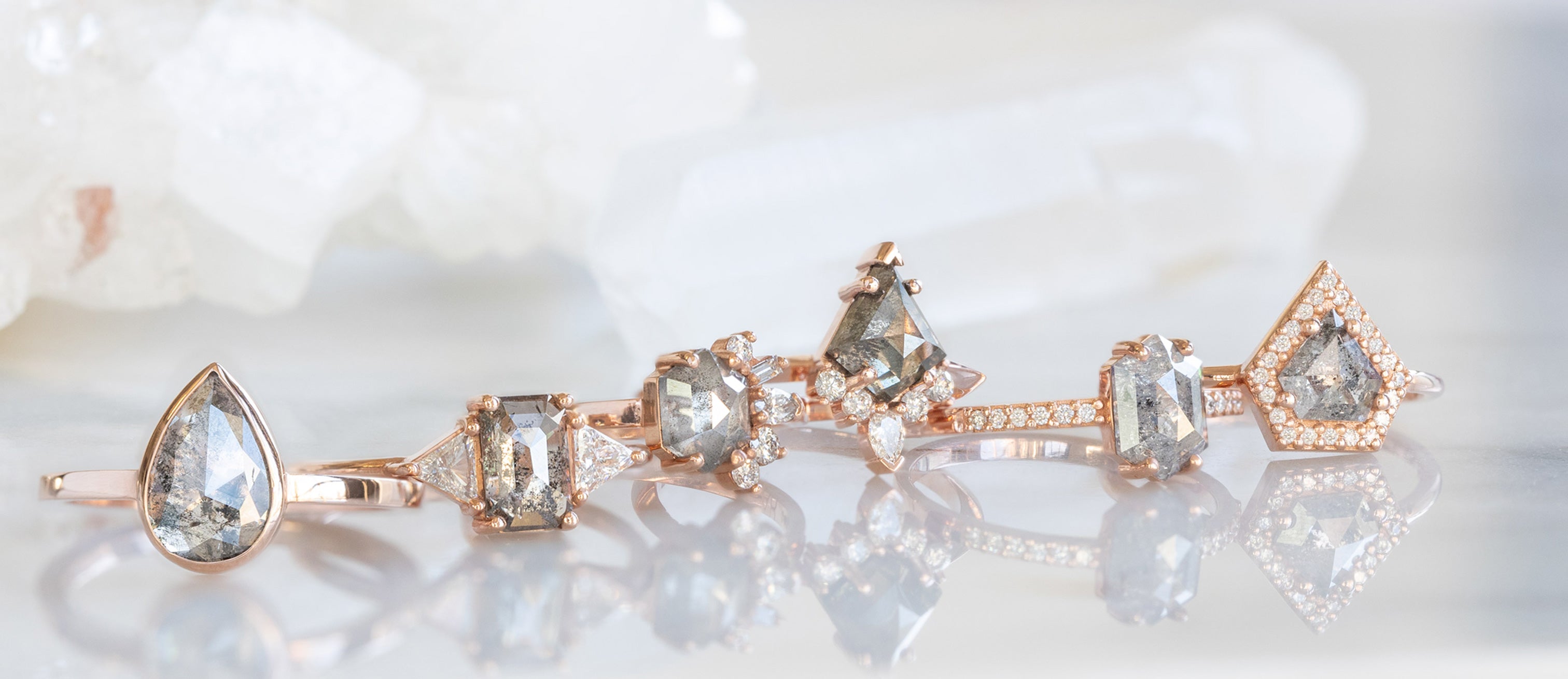 Line of Rose Gold Salt and Pepper Diamond Engagement Rings on Marble Tile