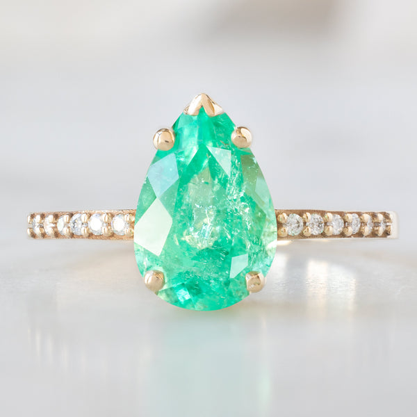 The Willow Ring with a 1.47ct Pear Emerald in 14K Yellow Gold on White Marble