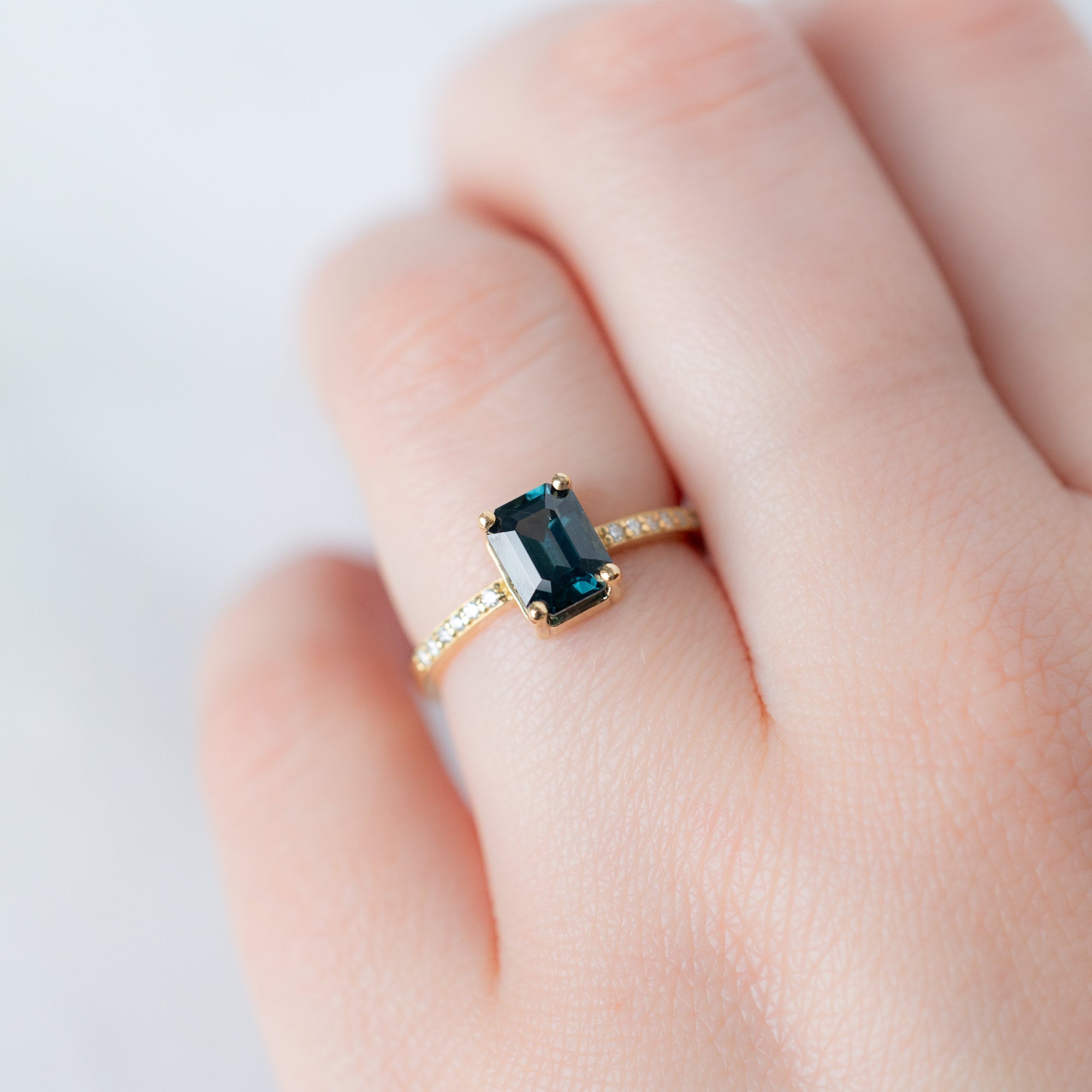 The Willow Ring with a 1.60ct Emerald Cut Teal Sapphire in 18K Yellow Gold on Model