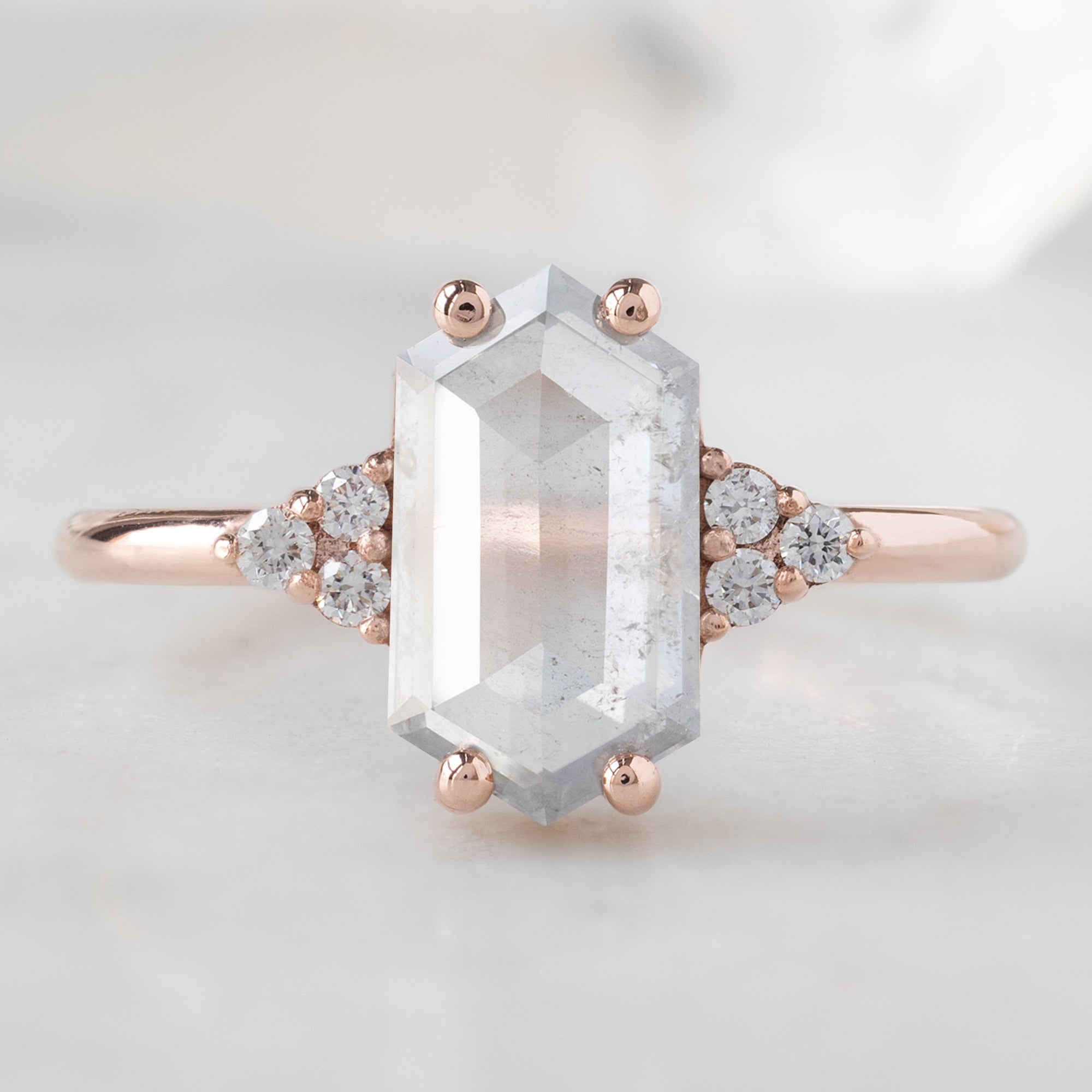 The Ivy Ring with a 1.55ct Hexagon Icy White Diamond in 14K Rose Gold on White Marble