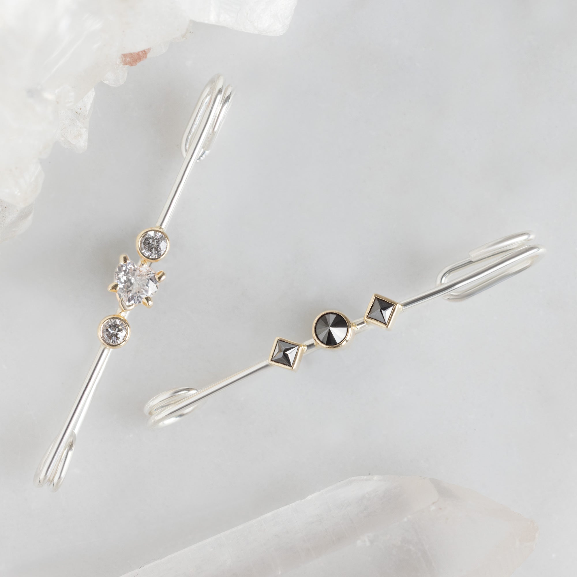Black Diamond and White Sapphire Safety Pin Brooches in Sterling Silver on White Marble Surface